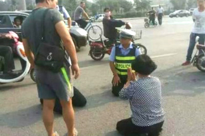 Хятадад замын цагдаа, дүрэм зөрчсөн явган зорчигч хоёр харилцан өвдөг сөхрөв